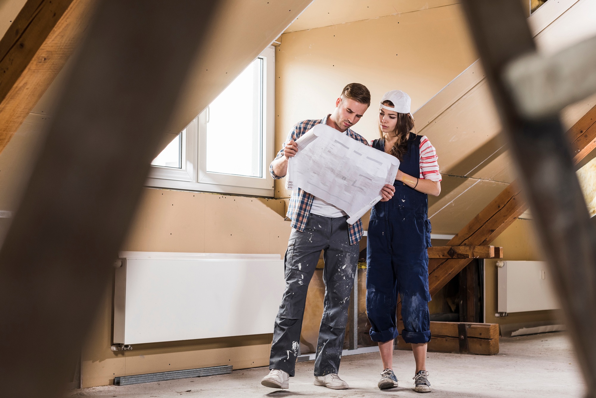 Young couple on construction site of their new home, looking at construction plan