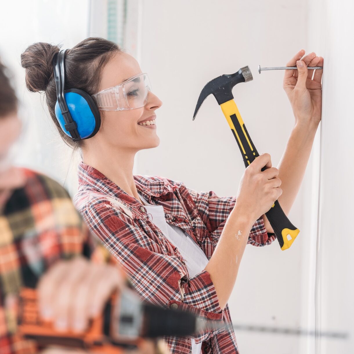 selective focus of young couple hammering and drilling wall during renovation