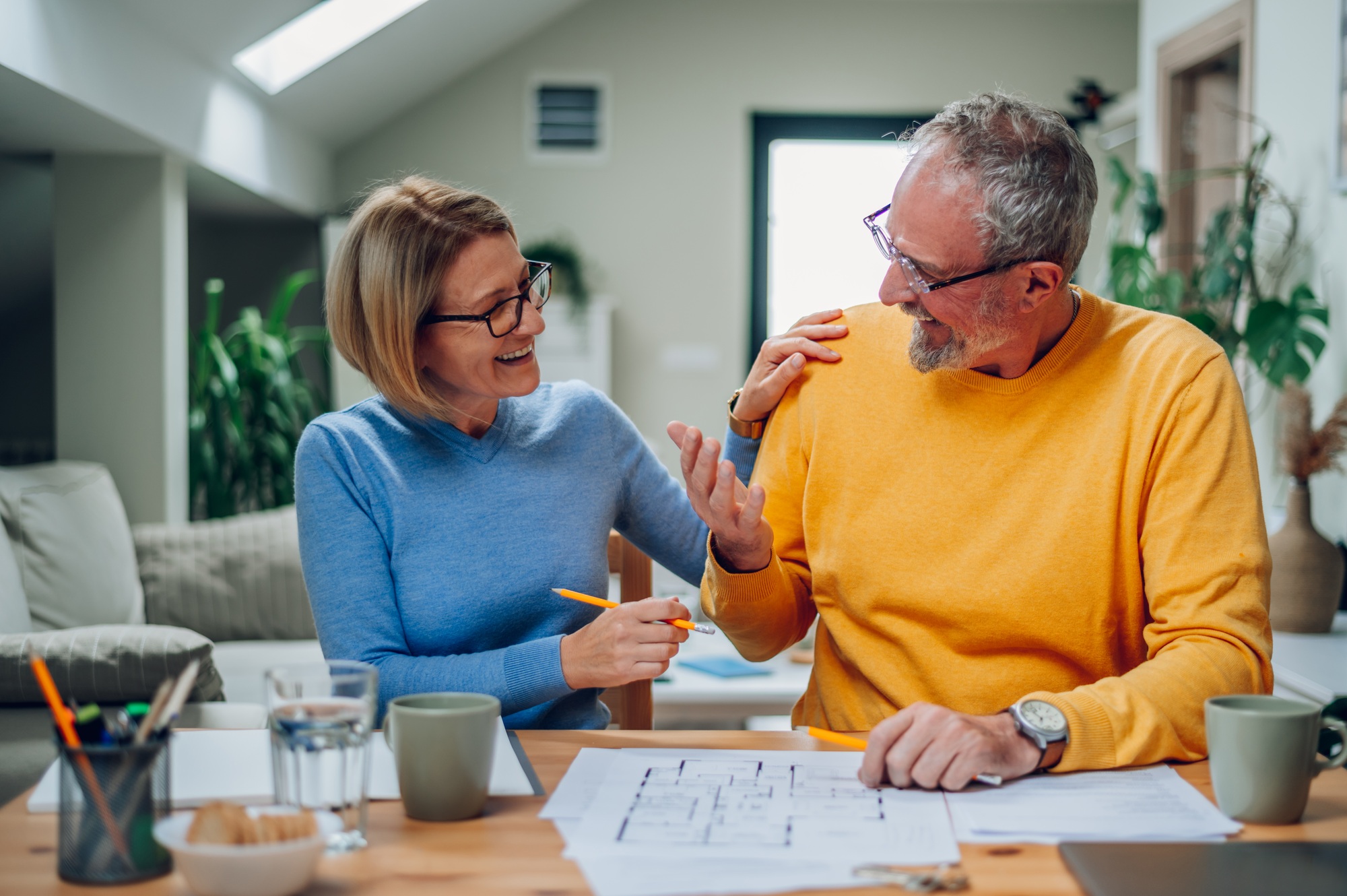 Senior couple sitting at table and looking into blueprints of their new home