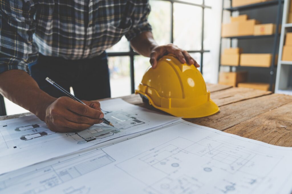 Engineer, architect laying out a drawing House plan design on blue print with accessories to put up